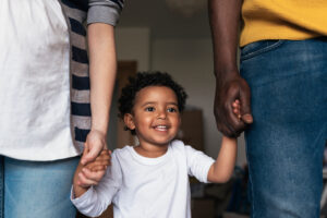 biracial family standing while little boy holds his parents hands